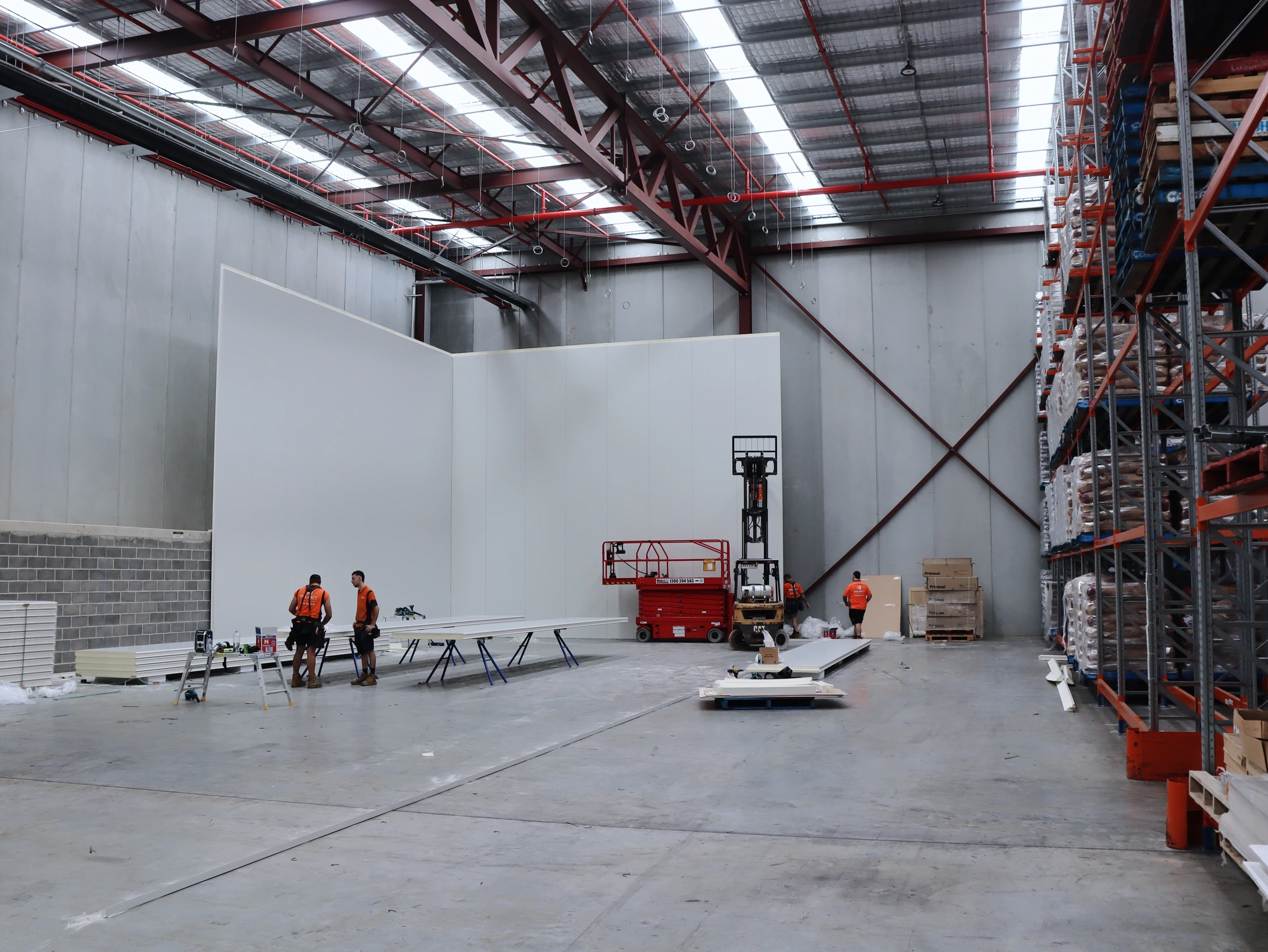 The main cool room walls standing at Chullora, with the crew, trestles and scissor lift working alongside the client's racking