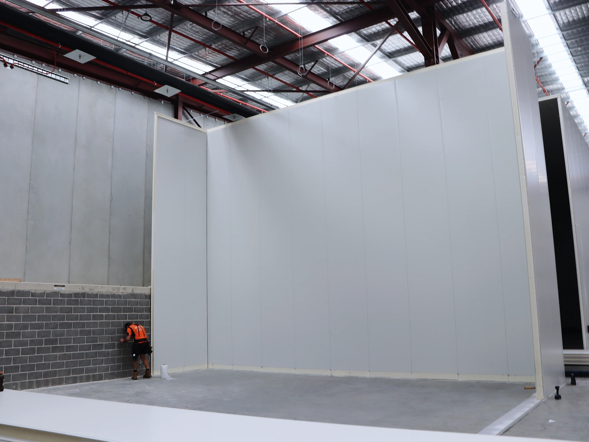 The corner of the Chullora cool room walls, an installer at the base for scale