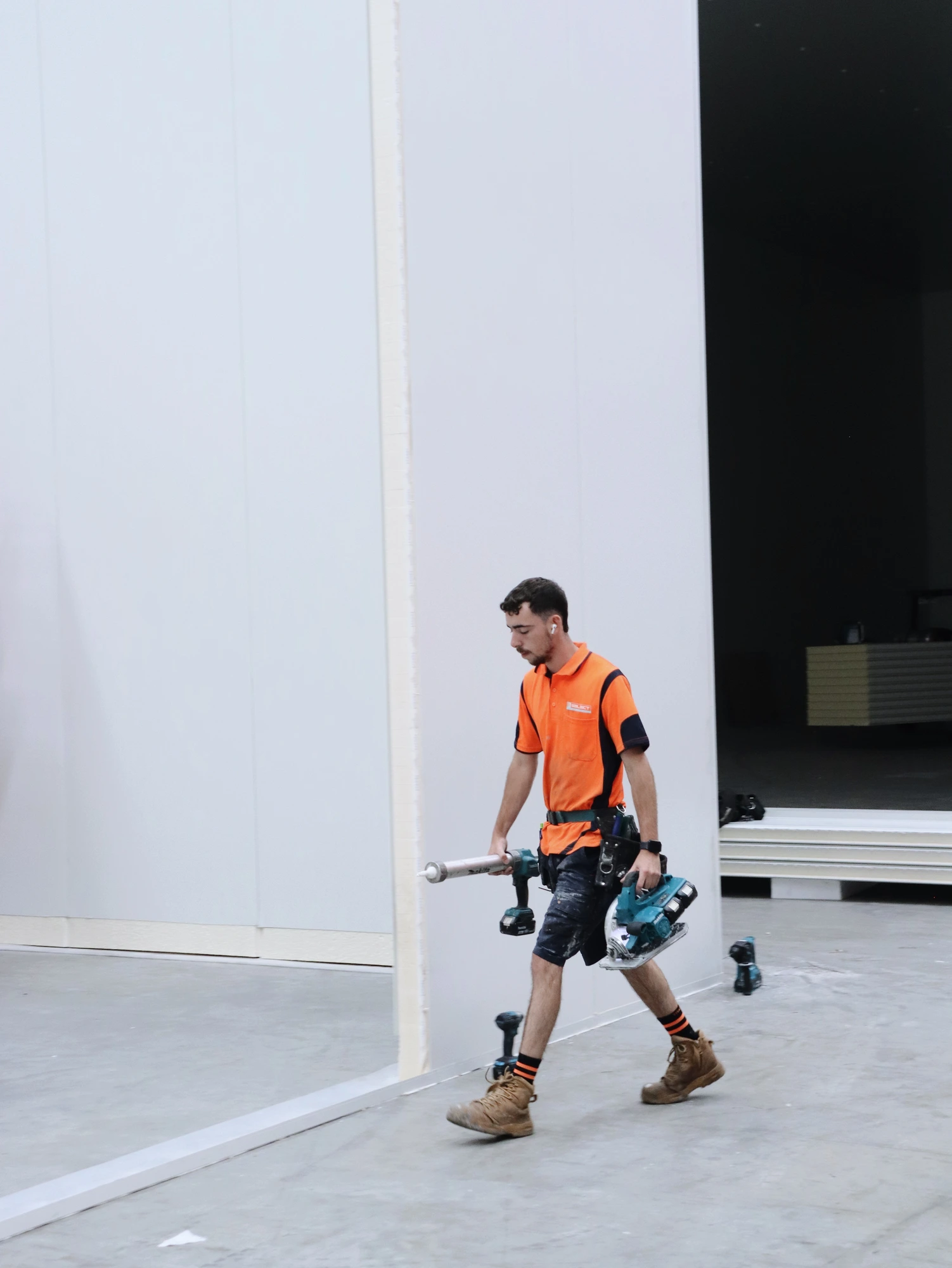 Installer carrying a sealant gun and cordless tools to the next joint at Chullora