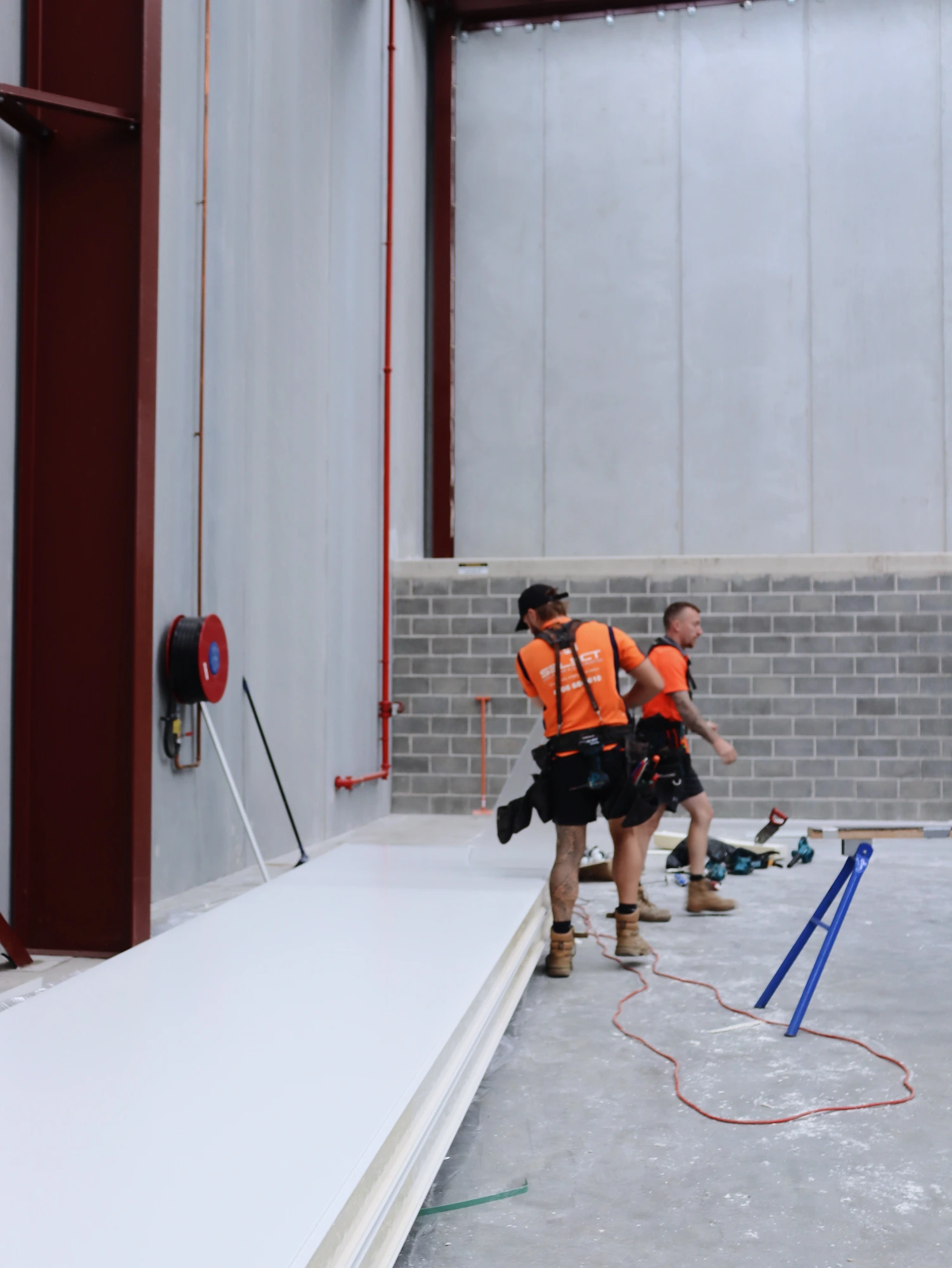 Two Select Coolrooms installers setting a panel at the base of the Chullora cool room wall