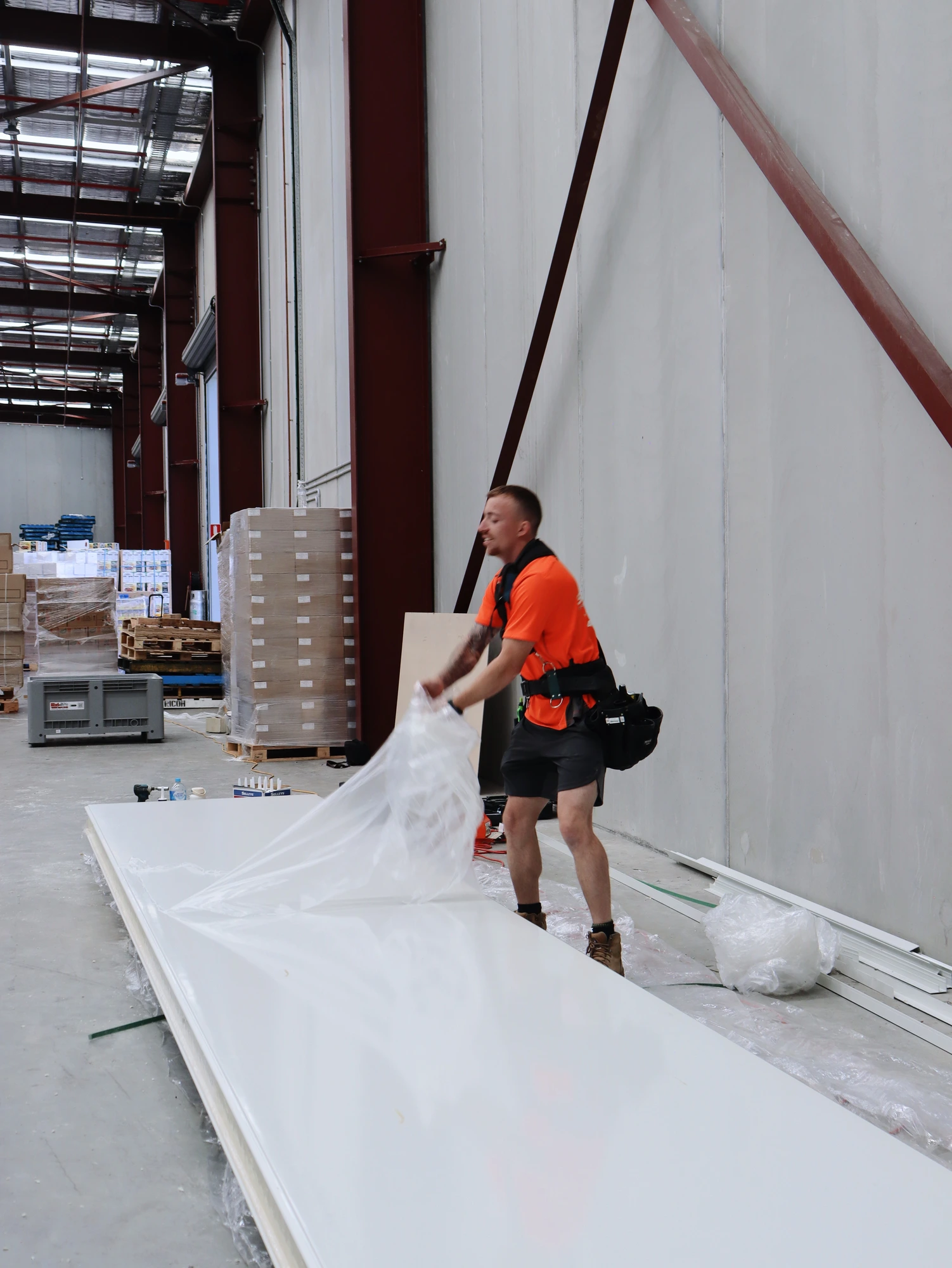 Installer pulling the protective film off a full length panel laid out ready to lift at Chullora