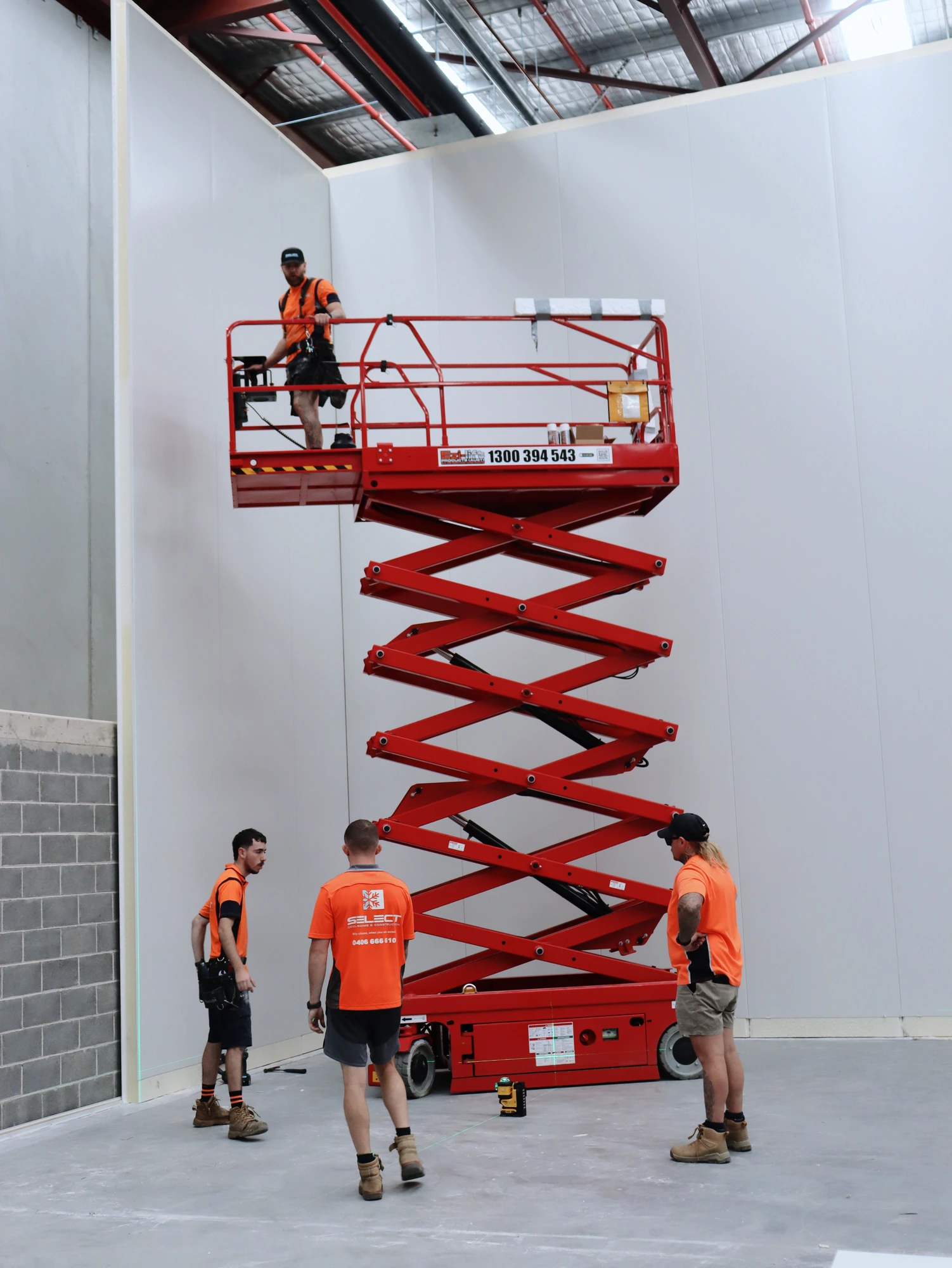 Select Coolrooms crew at the foot of a scissor lift extended up the full height of the Chullora cool room wall